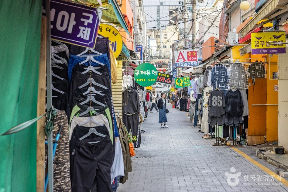 옷가게 간판이 빼곡히 걸린 국제시장 골목을 걷는 방문객들