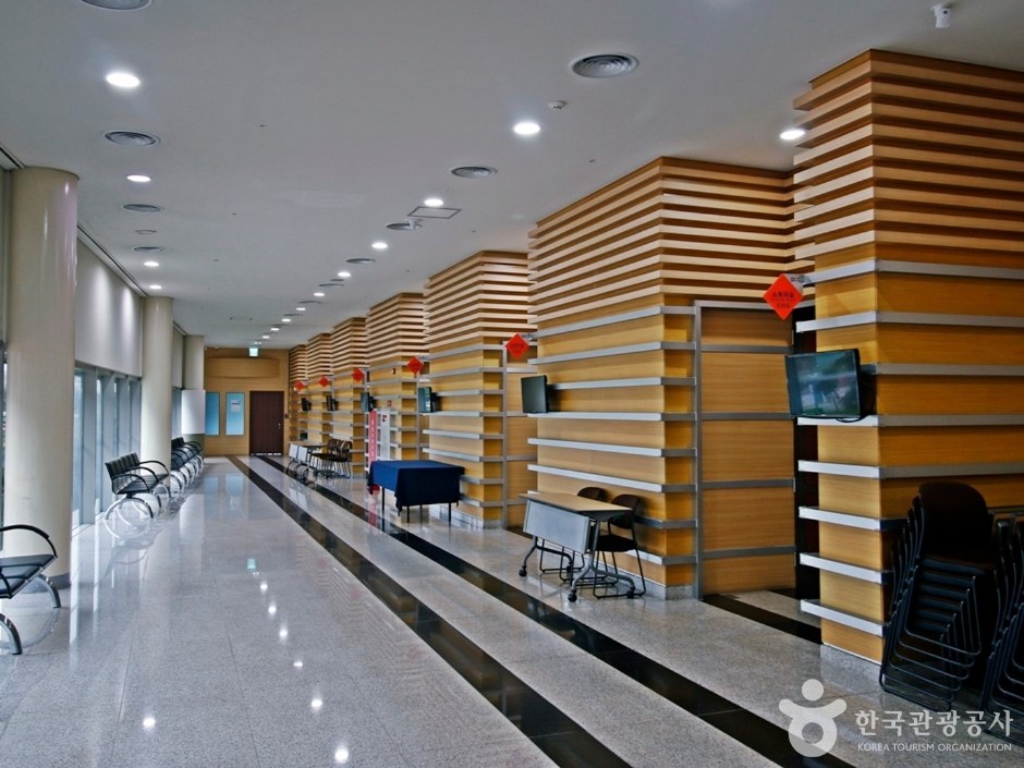 넓은 복도 양쪽에 나무 장식 벽이 이어진 컨벤션센터 내부 통로
