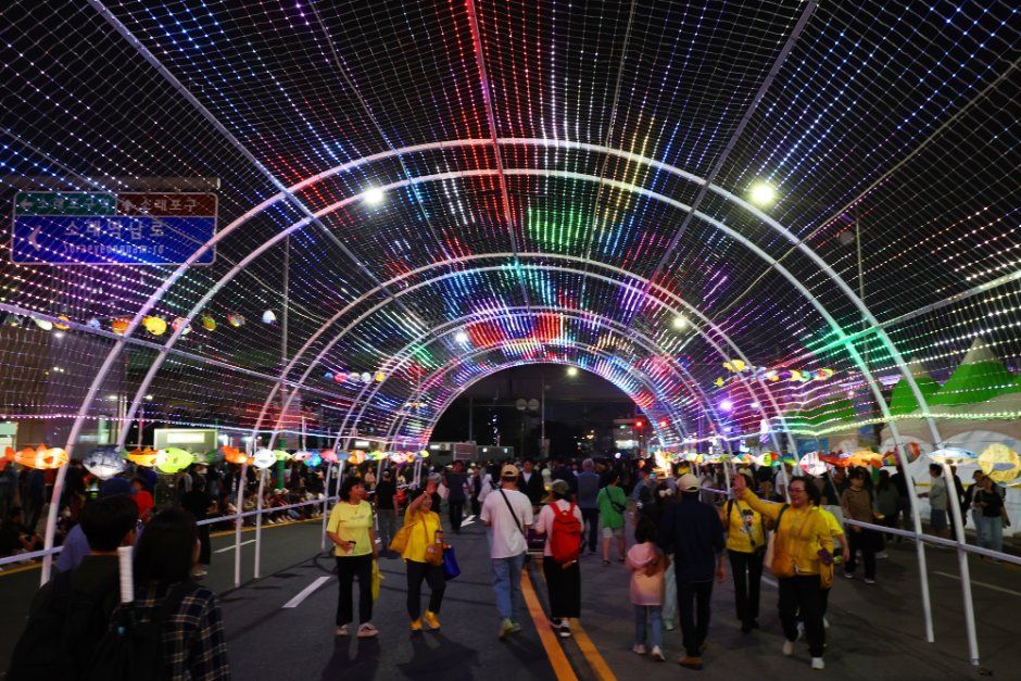 알록달록한 조명이 아치형 터널처럼 이어진 거리를 방문객들이 걸어가는 소래포구축제 야간 풍경